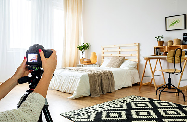 Real estate photographer using tripod to take photo of bedroom